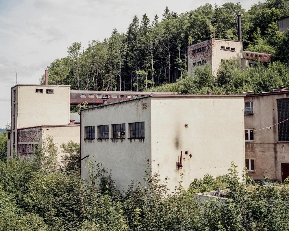 Zdjęcie przedstawiające opuszczoną, starą fabrykę przy lesie