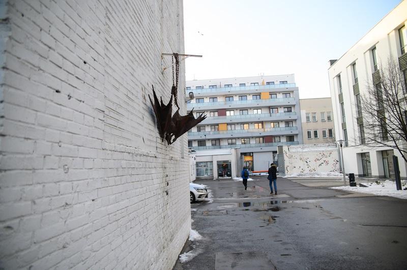 Żelazny nietoperz wiszący głową w dół na prawej ścianie budynku