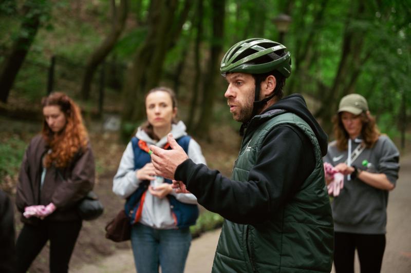 Instruktor wyjaśnia grupie woluntariuszy jak sadzić rośliny w parku