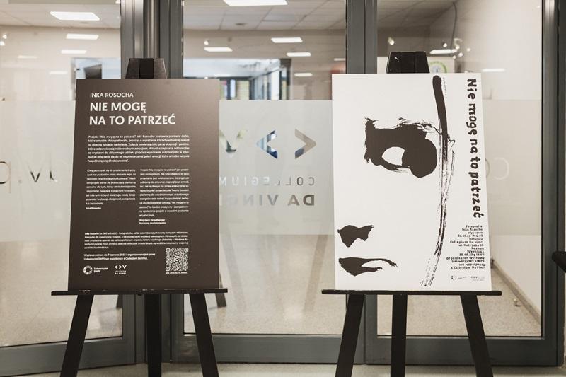 Dwa plakaty promujące wystawę, stojące na sztalugach przed wejściem na wystawę
