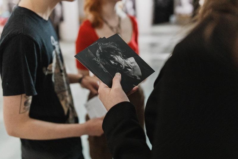 Dłoń trzymająca miniaturki fotografii z wystawy