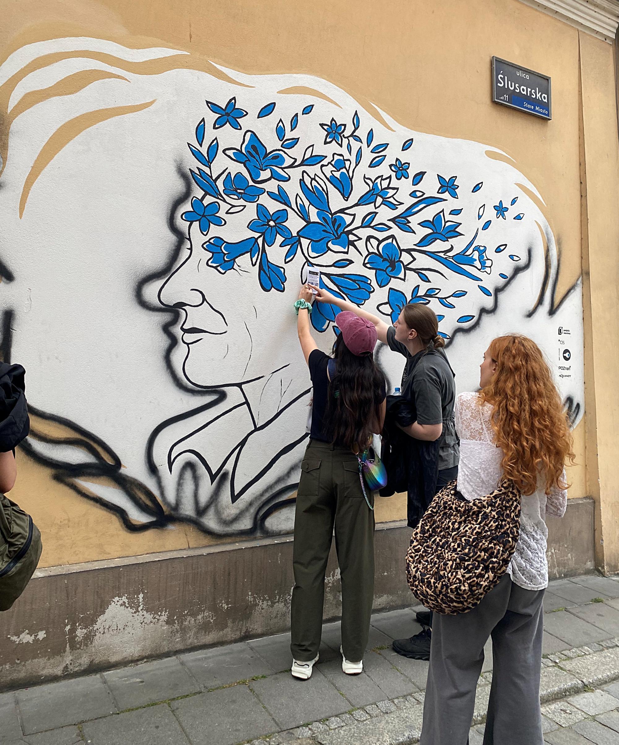 Studenci oglądają mural symbolizujący zdrowie psychiczne, Poznan, Polska