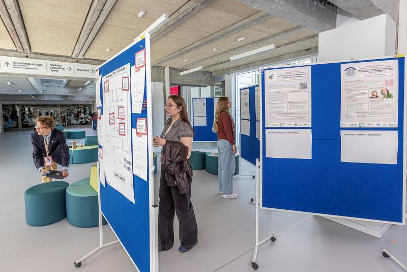 Studentki oglądają konferencyjne plakaty wystawione na korytarzu budynku