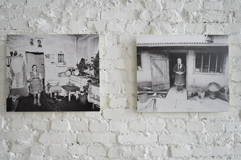 Dwie fotografie autorstwa Zofii Rydet wyeksponowane na ścianie. Na pierwszej widać kobietę stojącą w kuchni, gdzie widać sprzęty kuchenne i wystrój typowy dla lat 70.  Na drugim zdjęciu widać kobietę stojącą w progu domu. Na podwórku widać metalowe i drewniane kubły oraz grabie.