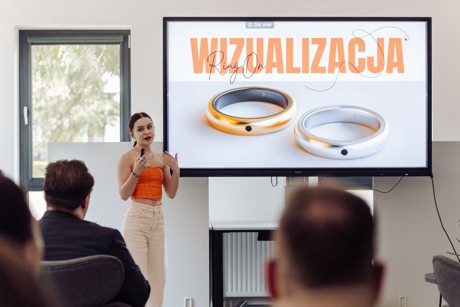 Dziewczyna wygłasza prezentację, w tle slajd z wizualizacją pierścionka RingOn