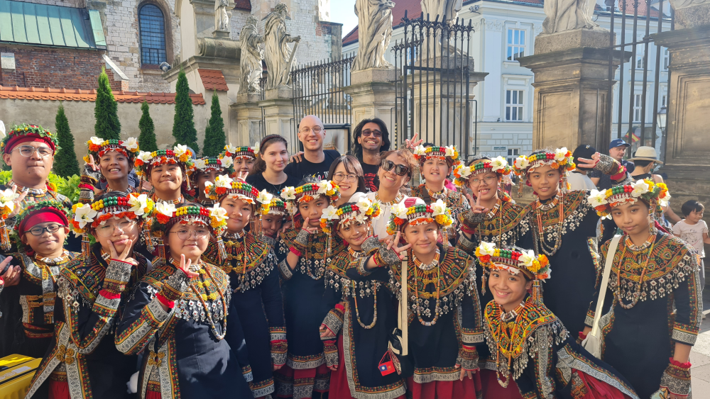 Zdjęcie grupowe. Kilkoro chórzystów USWPS z dużą grupą dzieci w tradycyjnych strojach ludu Paiwan