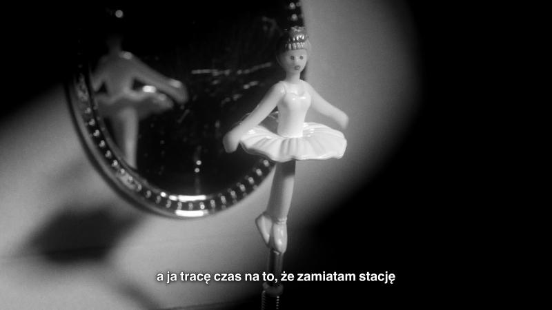Kadr z filmu Mileny Kowalczyk; na ekranie figurka baletnicy z pozytywki i fragment napisu: "a ja tracę czas na to, że zamiatam stację