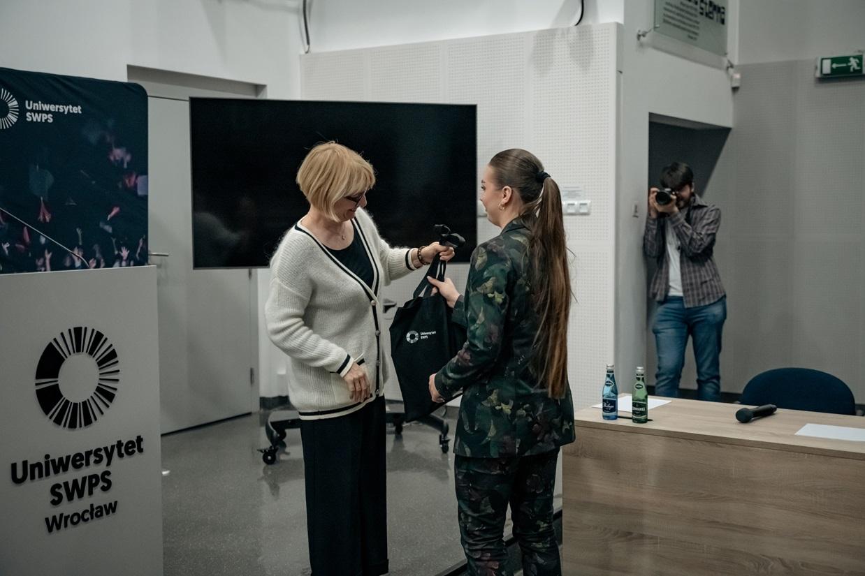 Monika Lewandowicz-Machnikowska wręcza torbę z logiem SWPS laureatce konkursu