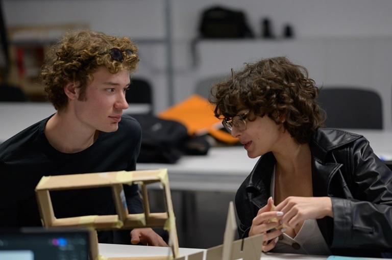 Student i studentka rozmawiający ze sobą siedząc przy stole