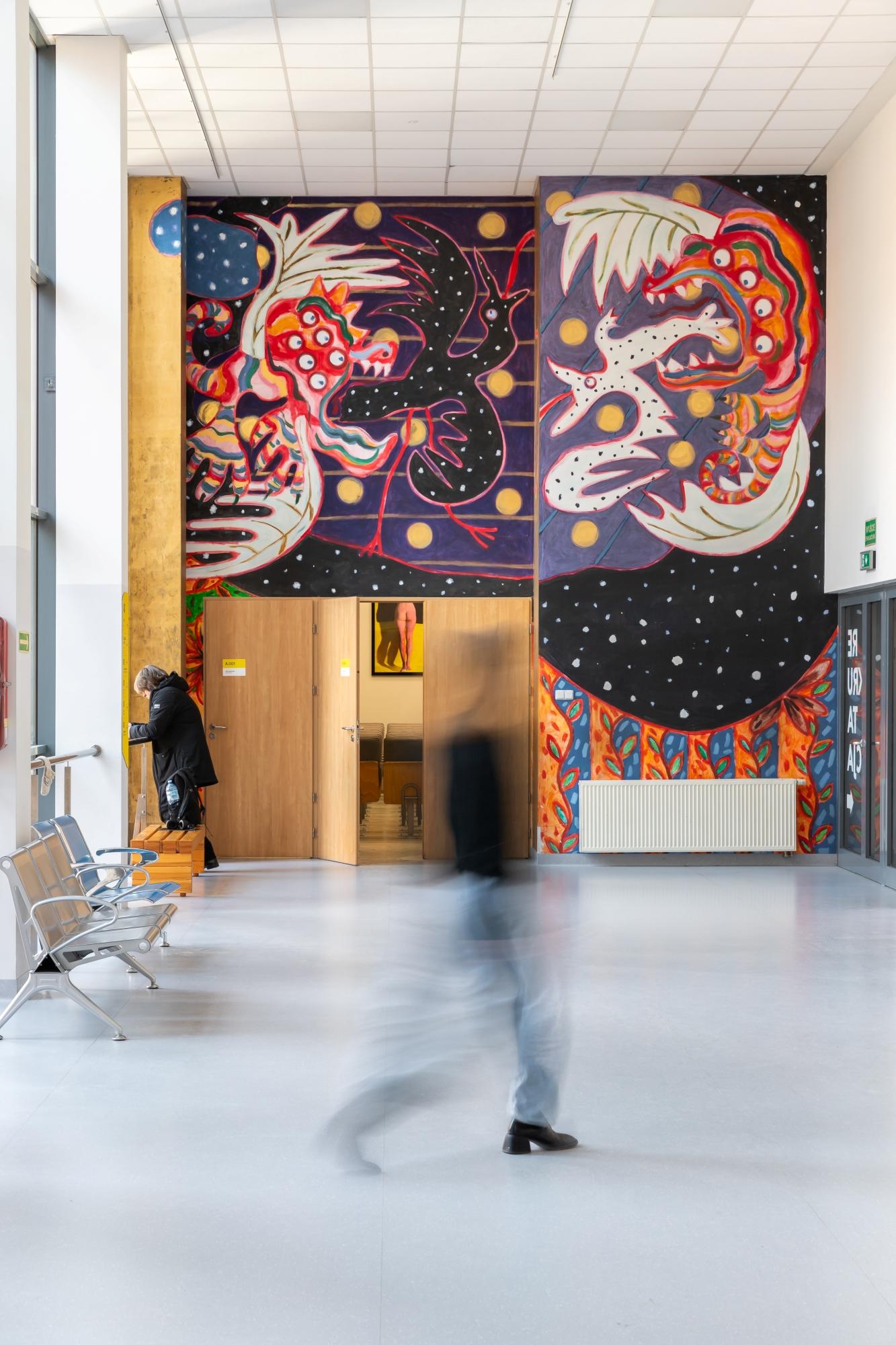 Mural Mariusza Kruka na ścianie Collegium Da Vinci w Poznaniu. Przedstawia abstrakcyjne smoki pożerające stwory przypominające ptaki.