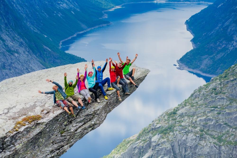 Grupa osób siedząca na skale, w tle krajobraz typowy dla Skandynawii