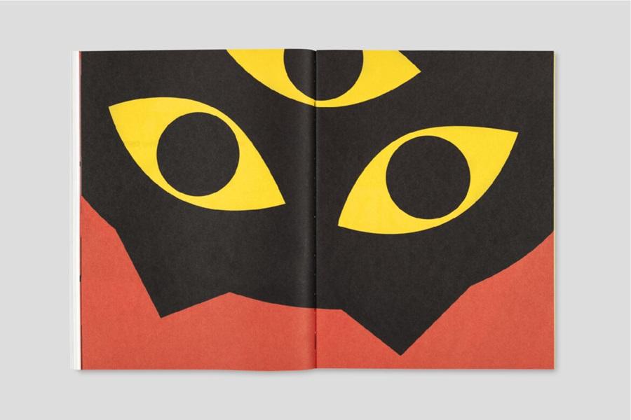 Otwarta książka. Na obu stronach widnieje ilustracja trójokiego, czarnego kota,który patrzy na czytelnika do góry nogami